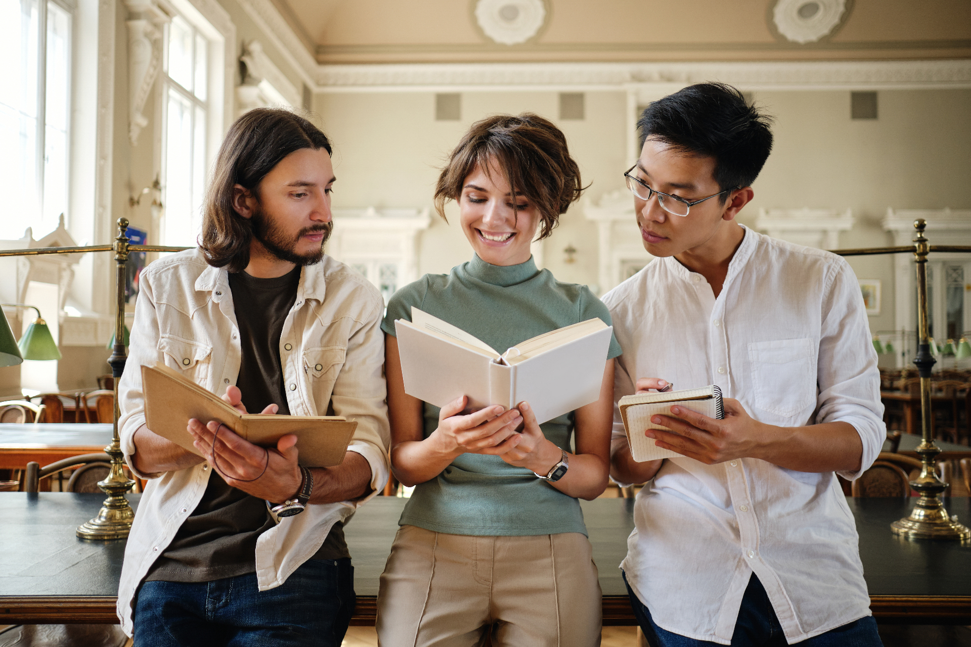 Three young students studying together with books in a university library